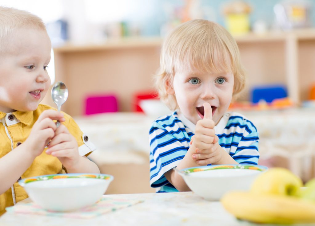 Kid eating in Nursery and showing thumbs up