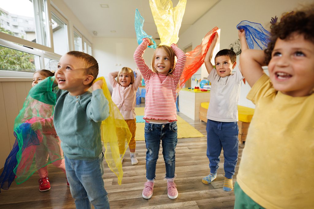 Children in playroom dance with scarves in their hands